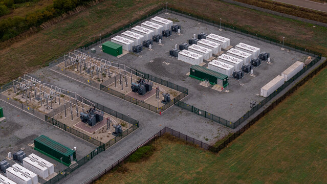 Aerial view of the Clay Tye Tesla Megapack installation with rows of white battery storage units and electrical transformers in a fenced site in Upminster, England, United Kingdom.