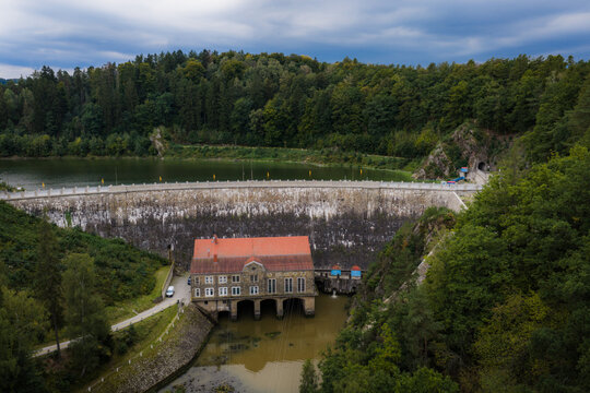 Aerial view of Zapora Zlotnicka dam with its historic stone building and red roof nestled among forests and the reservoir in Zlotniki Lubanskie, Lower Silesian Voivod, Poland.