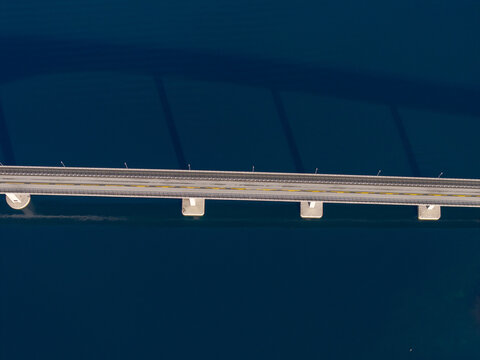 Aerial view of the Tresfjord Bridge spanning across deep blue water, showing its concrete pillars and road surface from directly above in Tresfjord, More og Romsdal, Norway.