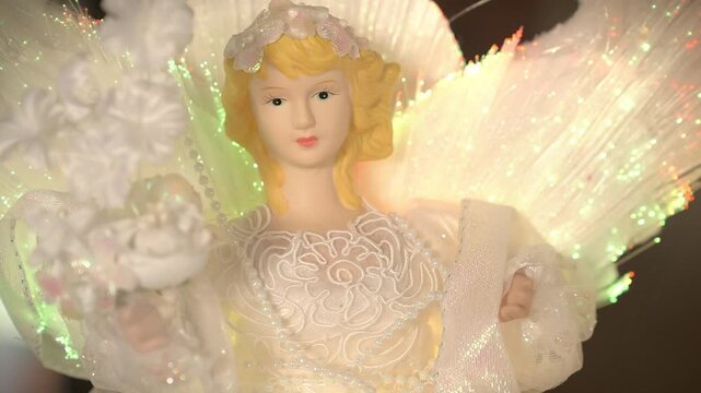 An electric, old-fashioned angel with blonde hair ornament with glowing lit-up wings. 