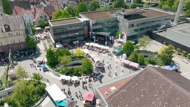 Aerial view of an event in the city centre with people, colourful umbrellas and surrounding buildings in sunny weather, Europamarkt, Nagold, Black Forest, Germany