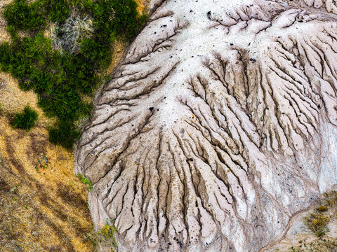 Aerial view of the eroded landscape at Tagebau Hambach, showing intricate drainage patterns and soil textures adjacent to patches of green vegetation, Elsdorf, Nordrhein-Westfalen, Germany.
