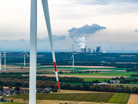 Aerial view of wind turbines with the Tagebau Hambach open-pit mine and power plant in the background, surrounded by agricultural fields in Elsdorf, Nordrhein-Westfalen, Germany.