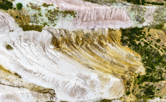 Aerial view of the textured landscape of Tagebau Hambach, showing layers of earth, erosion patterns, and patches of vegetation in Elsdorf, Nordrhein-Westfalen, Germany.