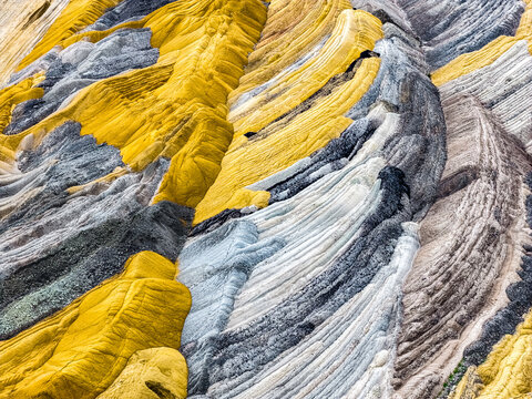 Aerial view of the colorful geological layers and textured terrain of the Tagebau Hambach open-pit mine in Elsdorf, Nordrhein-Westfalen, Germany.