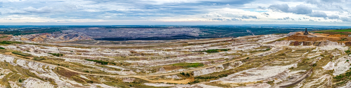Aerial view of Tagebau Hambach open-pit mine showing vast terraced excavation layers, industrial equipment, and expansive landscape under a cloudy sky in Elsdorf, Nordrhein-Westfalen, Germany.