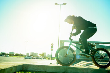 Naklejka premium BMX, man and bike in city for sports, urban challenge and exercise with space. Person, riding bicycle and cyclist on curb outdoor for fitness, extreme cycling and balance for stunt with flare