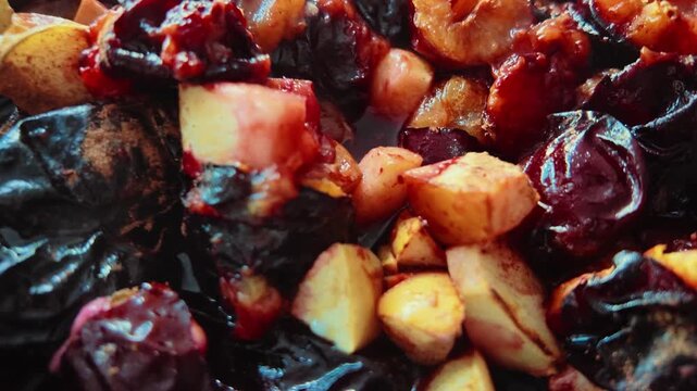 Close-up video of fresh plums and apple pieces baking on a tray in the oven. Warm homemade fruit dessert with caramelized fruit, ideal for food, baking, healthy eating and homemade cooking concepts.