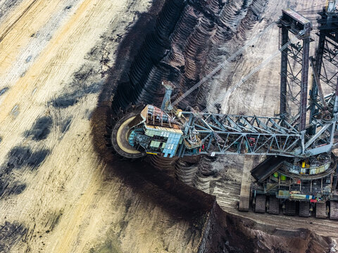 Aerial view of the Garzweiler surface mine featuring a massive bucket-wheel excavator digging into the earth with deep soil layers in Juchen, North Rhine-Westphalia, Germany.