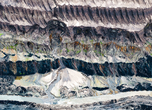Aerial view of the Garzweiler surface mine showing deep excavated layers, exposed coal seams, and sediment runoff in Juchen, North Rhine-Westphalia, Germany.