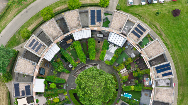 Aerial view of a circular residential housing complex featuring private gardens, flat roofs with solar panels, and a central green area in Houten, Utrecht, Netherlands.