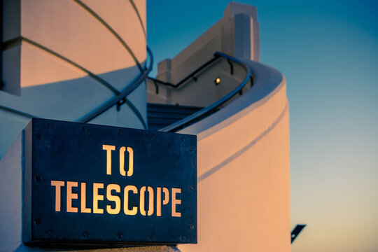 View of the TO TELESCOPE sign with stencil lettering mounted on a curved white wall at Griffith Observatory in Los Angeles, California, United States.