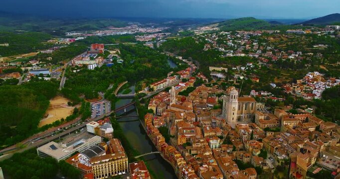 Aerial view of the charming historic city of Girona in Spain, known for its medieval streets, colorful houses along the Onyar River, ancient bridges, and majestic cathedral