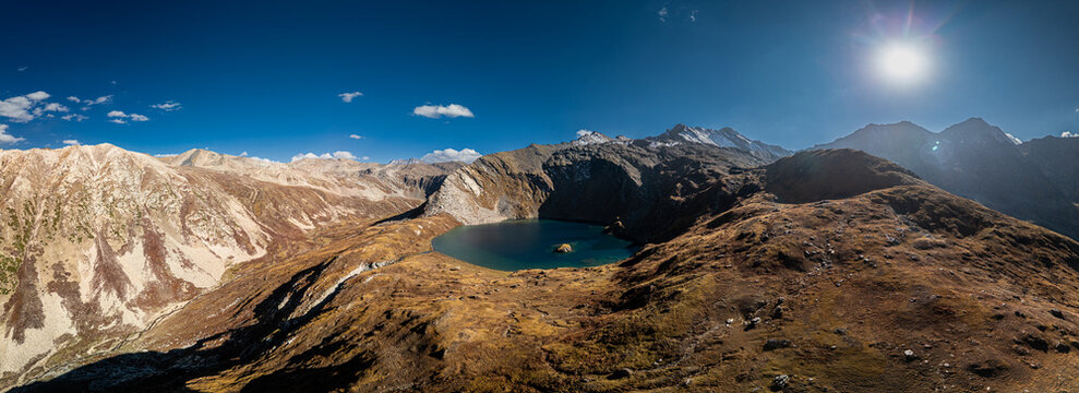 Aerial view of Maheen Lake nestled among rugged mountain peaks and rocky slopes under a clear blue sky in Batakundi, Khyber Pakhtunkhwa, Pakistan.