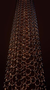 Carbon nanotube turning slowly, an armchair tube of carbon atoms lit from inside, vertical video loop