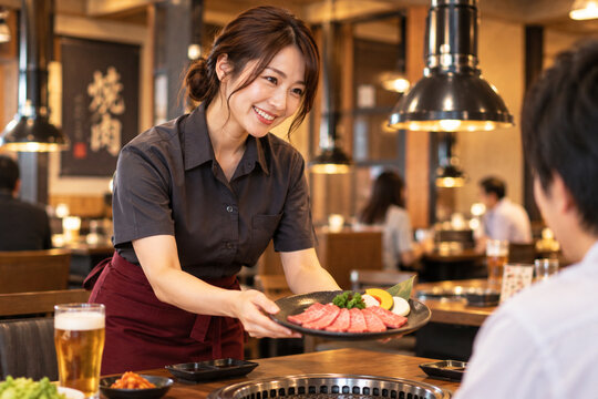 笑顔で焼肉を運ぶホールスタッフの女性