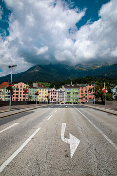 View of a street leading towards colorful historic buildings with mountains in the background under a cloudy sky in Schwangau, Bavaria, Germany.