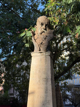 A bust of Claude Monet stands on an inscribed stone pedestal surrounded by leafy trees - Rouen, France - September 6, 2026