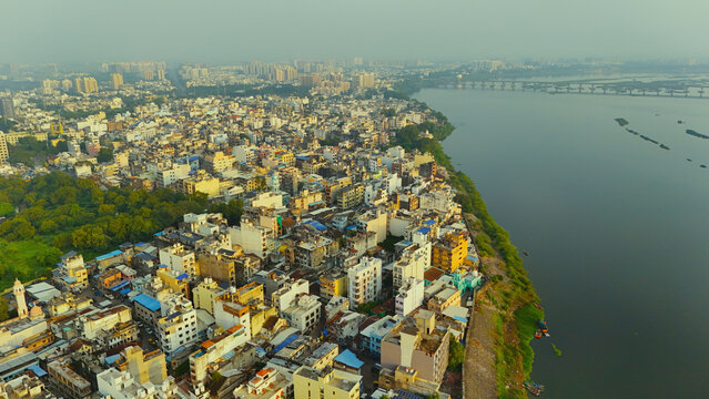 Aerial view of the dense urban landscape along the Tapi River, featuring historic buildings, rooftops, and a bridge in the distance in Surat, Gujarat, India.