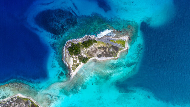 Aerial view of Los Roques archipelago with a small island surrounded by turquoise Caribbean waters, coral reefs, and white sandy beaches in Los Roques, Dependencias Federale, Venezuela.
