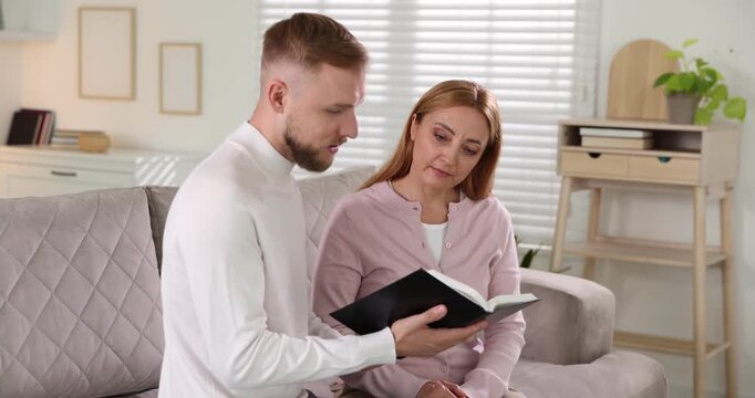 Pastor conducting Bible study with woman on sofa indoors