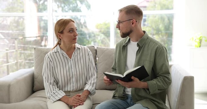 Pastor conducting Bible study with woman on sofa indoors