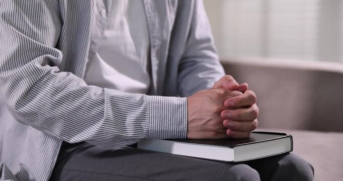 Pastor with Holy Bible praying on sofa indoors, closeup