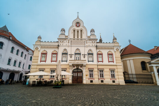 View of the historic Bishops Palace with its ornate facade and arched entrance in the cobblestone Unirii Square in Timisoara, Timis, Romania.