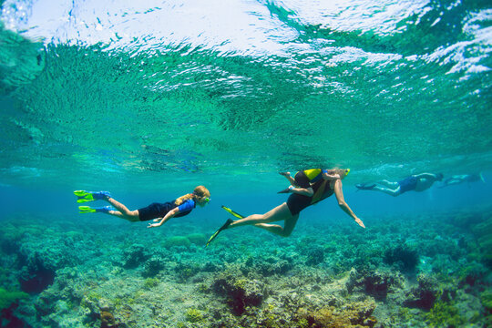 Happy family - active kids with mother in snorkeling mask dive underwater, see tropical fishes in coral reef sea pool. Travel adventure, swimming activity and watersports on summer beach vacation.
