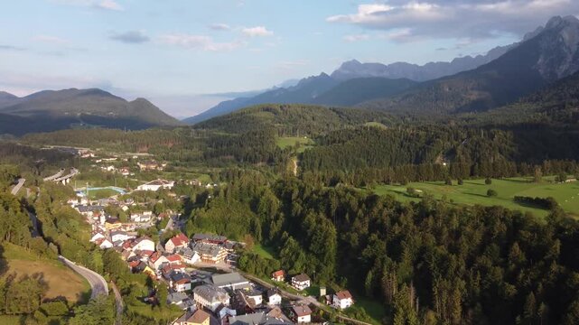 Aerial Flight over Tarvisio Town in Alpine Valley with Motorway Viaduct and Mountains, Italy. Ideal establishing shot for travel videos, regional advertising and documentary projects.
