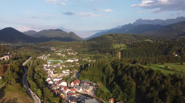 Aerial Flight over Tarvisio Town in Alpine Valley with Motorway Viaduct and Mountains, Italy. Ideal establishing shot for travel videos, regional advertising and documentary projects.