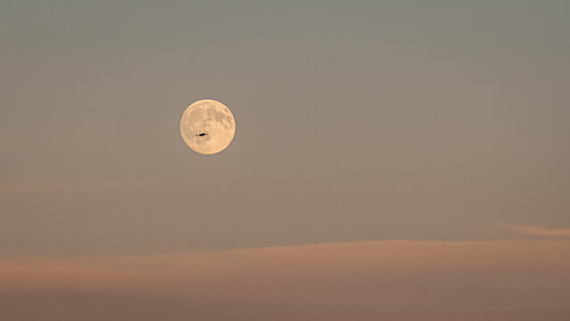 View of a drone silhouetted against the full moon in the evening sky in Vesancy, Auvergne-Rhone-Alpes, France.