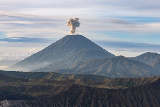Mount Bromo volcano at sunrise, viewed from King Kong viewpoint in Bromo Tengger Semeru National Park, East Java, Indonesia. Active crater smoke, Mount Semeru cone, clouds, and vast ash plain.