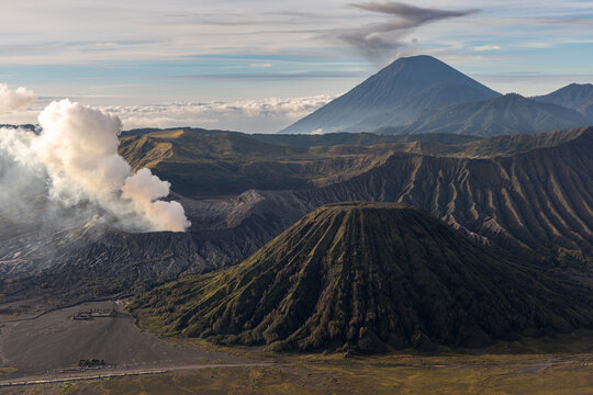 Mount Bromo volcano at sunrise, viewed from King Kong viewpoint in Bromo Tengger Semeru National Park, East Java, Indonesia. Active crater smoke, Mount Semeru cone, clouds, and vast ash plain.