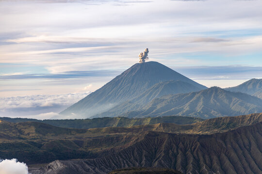 Mount Bromo volcano at sunrise, viewed from King Kong viewpoint in Bromo Tengger Semeru National Park, East Java, Indonesia. Active crater smoke, Mount Semeru cone, clouds, and vast ash plain.