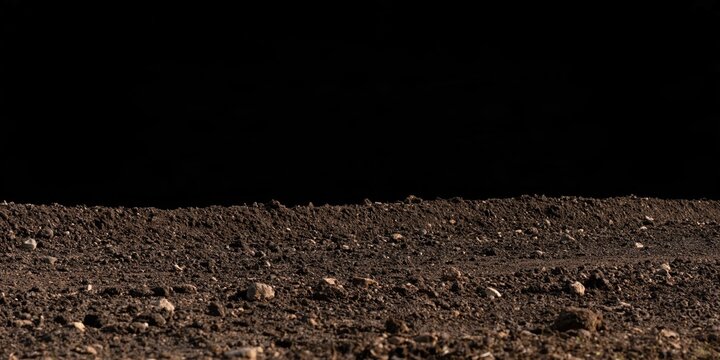 Close-up of dark soil with stones against black background