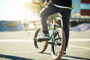 Naklejka premium Bicycle, legs and person for outdoor hobby, activity or challenge in urban skate park. Bike, shoes and feet for cycling, BMX training and skills for competition in city for balance and stunt exercise