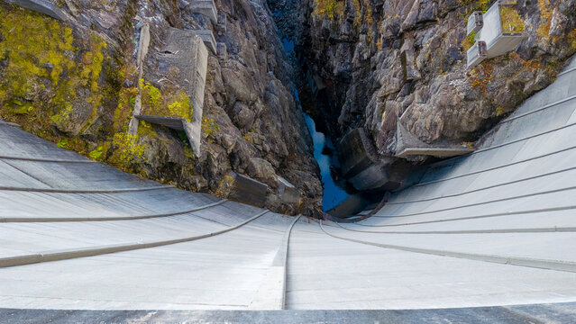 View of the concrete structure of Zakarias Dam set against the steep, rugged rock walls of a deep gorge in Tafjord, More og Romsdal, Norway.