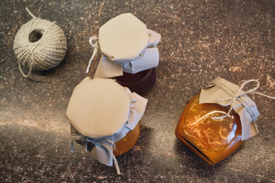 Glass jars of homemade preserves wrapped in craft paper and tied with natural twine