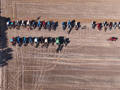 Covehithe, United Kingdom - 05 October 2026: Aerial view of colorful tractors parked in neat rows on a plowed agricultural field with visible tire tracks under bright sunlight.