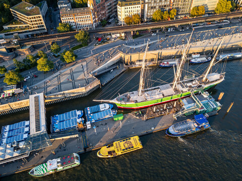 Hamburg, Germany - 04 October 2026: Aerial view of the historic Rickmer Rickmers sailing ship docked at the Landungsbruecken, surrounded by tourist boats, urban infrastructure, and city buildings.