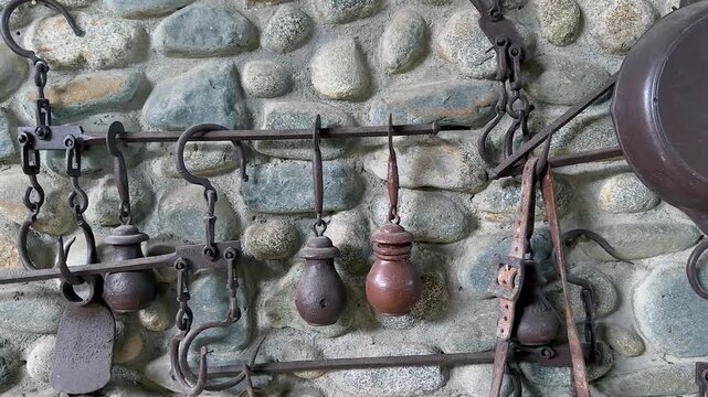 vintage iron hanging weights and scale tools displayed on rustic stone wall