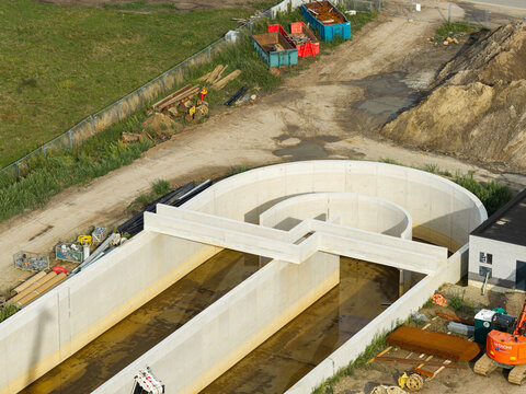 Diepenbeek, Flanders, Belgium - 30 August 2026: Aerial view of the wastewater treatment plant construction site featuring concrete basins and infrastructure.