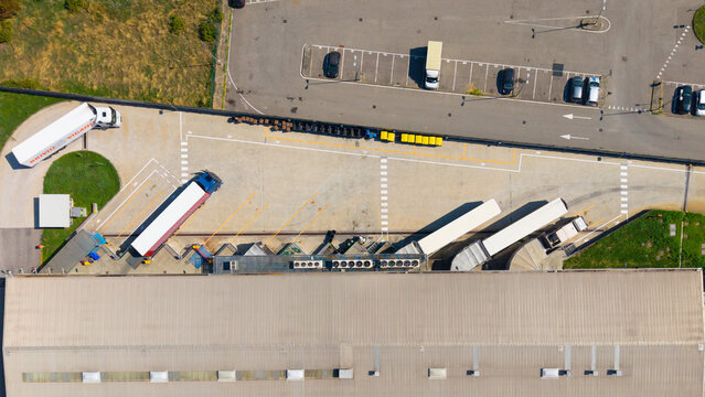 Sesto Ulteriano, Italy - 04 September 2026: Aerial view of a large food distribution warehouse with trucks parked at loading docks and a parking lot.