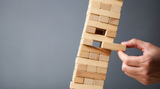 Business strategy growth roadmap with careful hand removing wooden block from leaning tower during tense challenge of balance and risk
