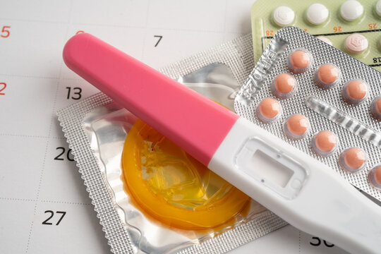 Pregnancy test and birth control pills on calendar, contraception health and medicine.