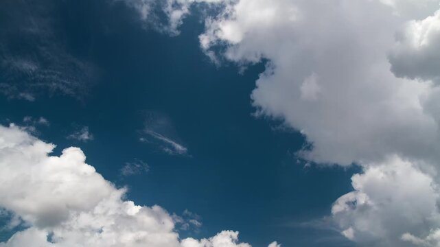 Time-lapse of fluffy white cumulus clouds drifting across a vivid blue sky, serene and dynamic natural scene