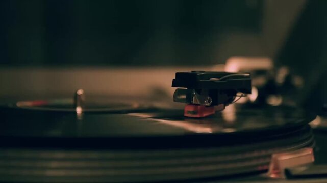 Close-up of a vinyl record player turntable with tonearm and cartridge playing a spinning LP in warm ambient lighting