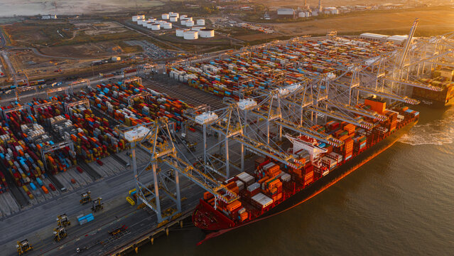 Corringham, England, United Kingdom - 25 September 2026: Aerial view of London Gateway port with container ships, cranes, and rows of colorful shipping containers at sunset.
