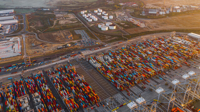 Corringham, England, United Kingdom - 25 September 2026: Aerial view of London Gateway container terminal with rows of colorful shipping containers and industrial storage tanks.